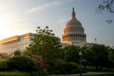 US Capitol dome at golden-hour sunrise, framed by trees