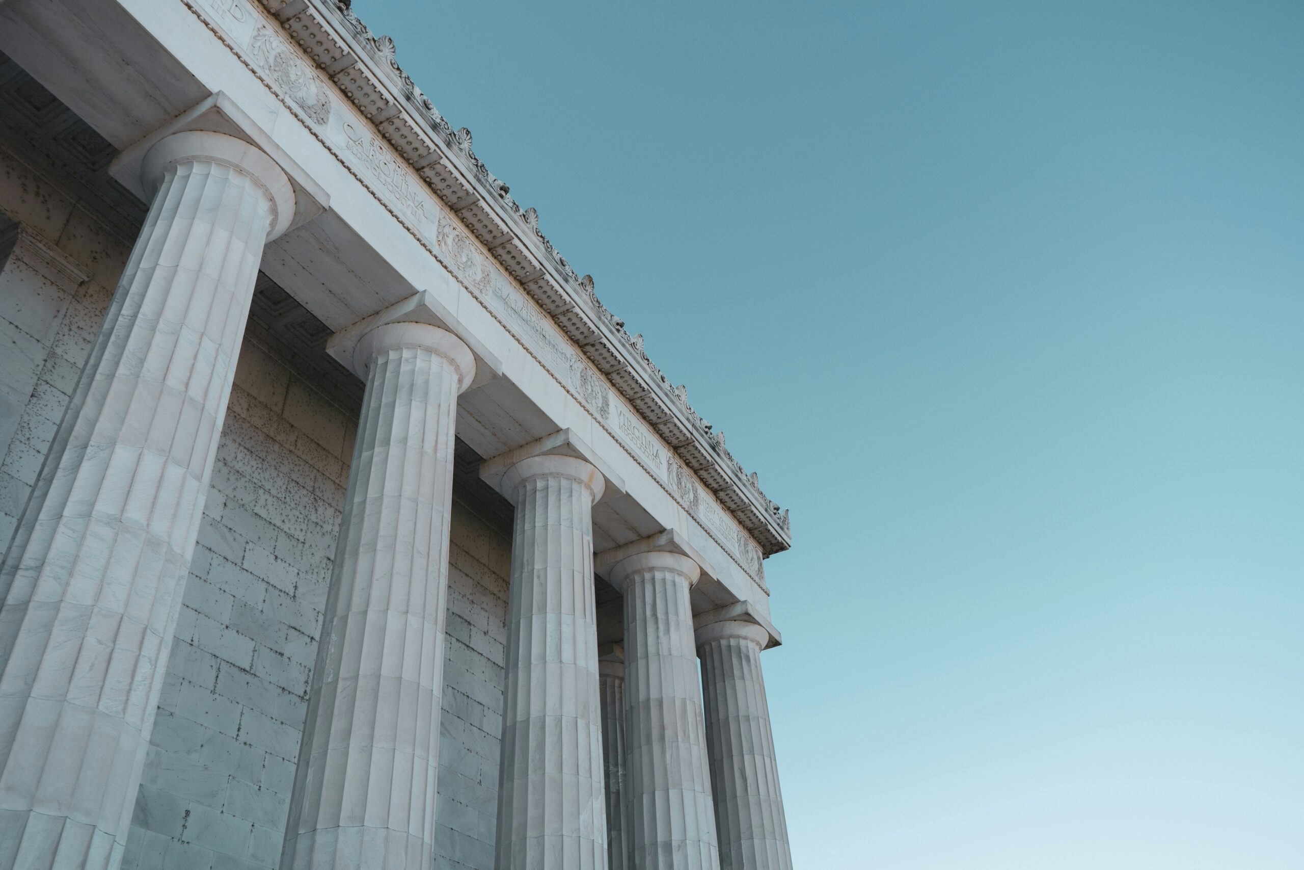 Close-up of neoclassical stone columns on a civic building against a teal sky